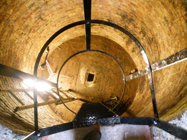 Photo of interior of the ice house looking down to the drain in the brick-lined floor.